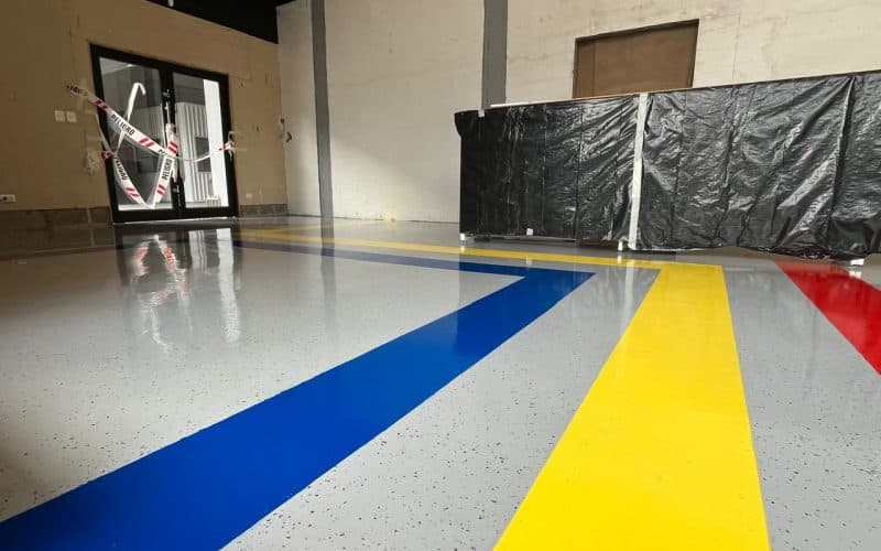 Piso epóxico con demarcación azul y amarilla recién aplicada